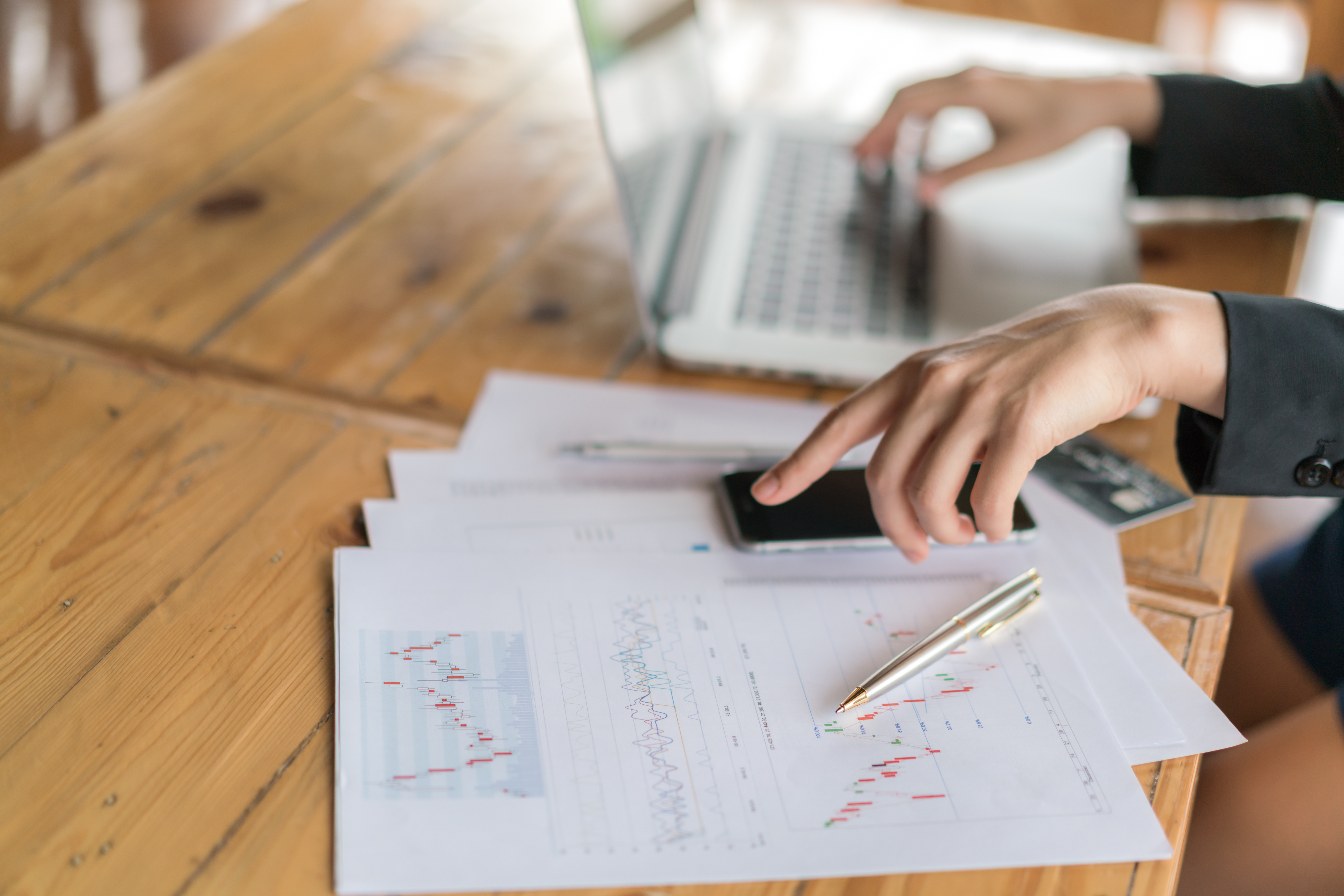 business woman hand with financial charts and laptop on the tabl